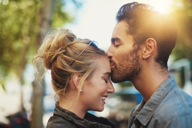 a boyfriend kissing his girlfriend’s forehead
