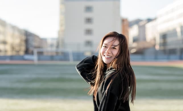 a young asian woman is posing outdoors