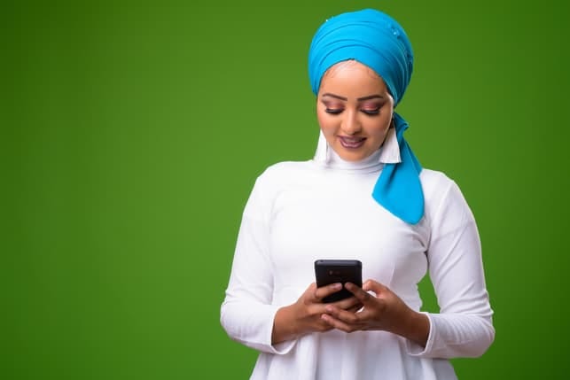 a young dark-skinned girl in a traditional clothing using her smartphone