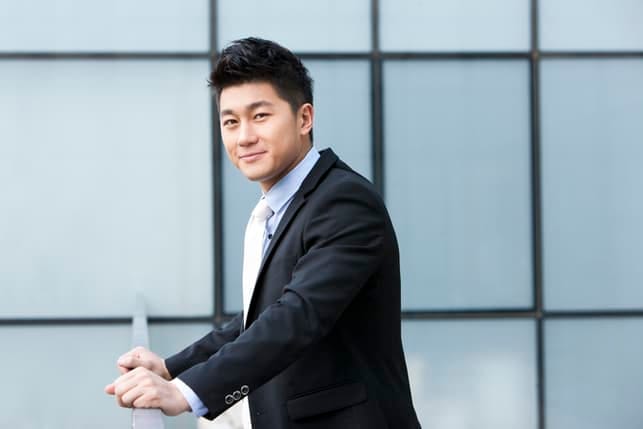 a young asian man in a suit posing outdoors