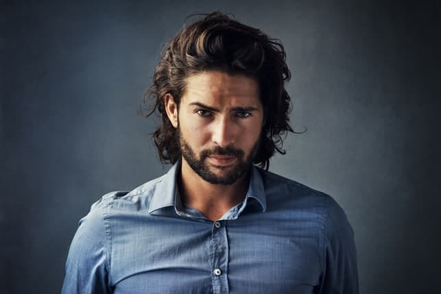 an attractive dark-haired man in a blue shirt posing