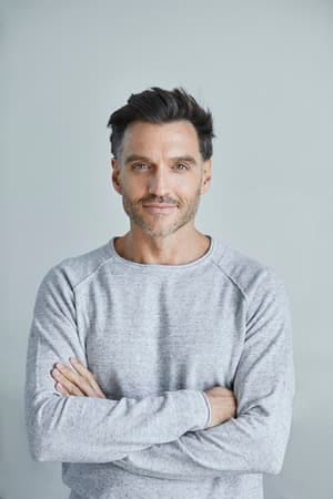 a serious and confident man posing indoors