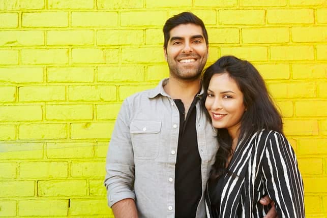 an oriental couple posing together on a yellow brick wall background