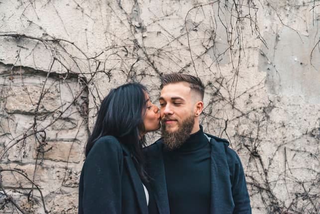 a girl kissing her boyfriend’s cheek