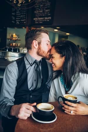 a man kissing his girlfriend’s forehead