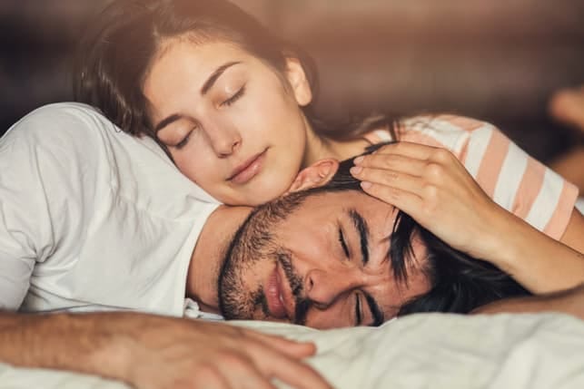 a couple is sleeping together while hugging