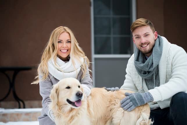 a beautiful couple with a dog smiling while spending time outdoors